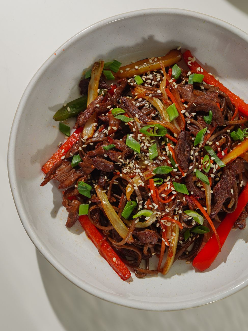 Finished jjapaguri with seared steak, sesame seeds, and scallions